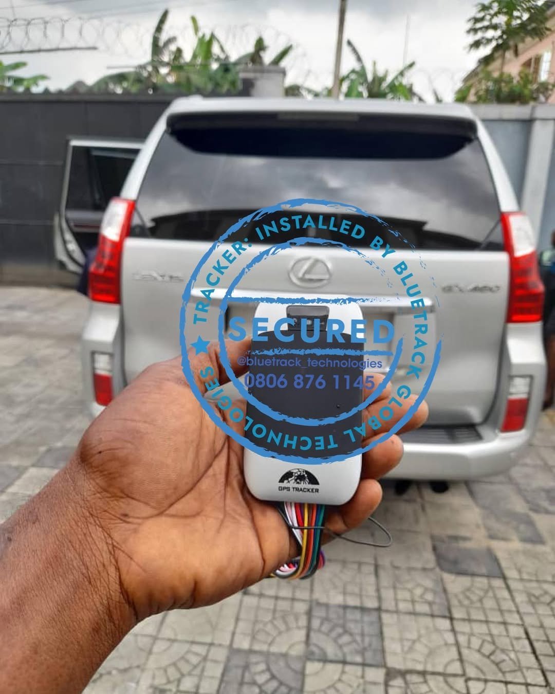 Person holding a circular blue security sticker with vehicle dashboard technology information in front of a parked silver SUV