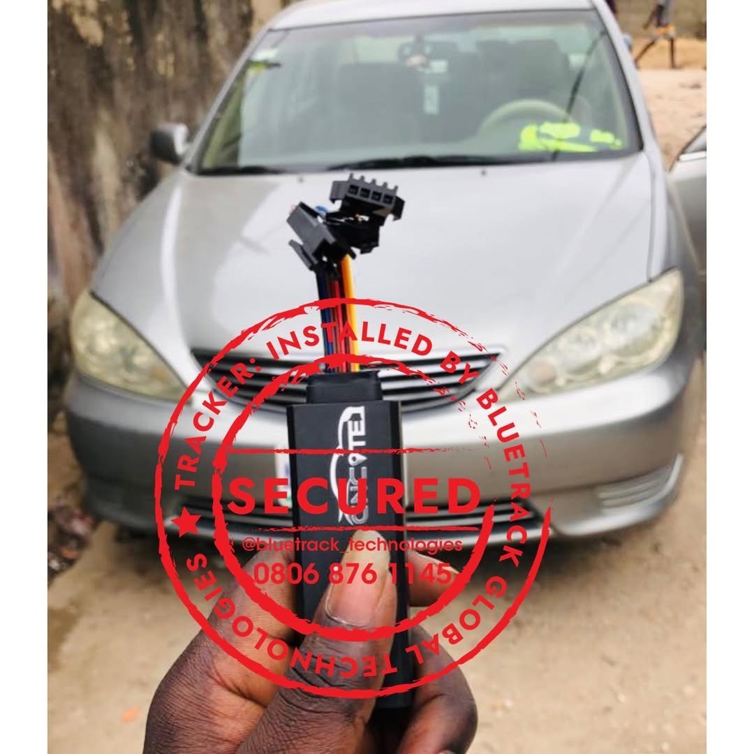 Person holding a red circular automotive part tool in front of a white sedan car